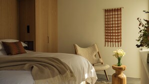 A modern bedroom with a bed, a chair, a wooden wardrobe, and a wall-mounted tapestry. - Fowlescombe Farm (Ivybridge)