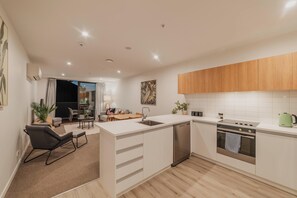 A modern kitchen with white cabinetry, a built-in dishwasher, and a stainless steel oven.