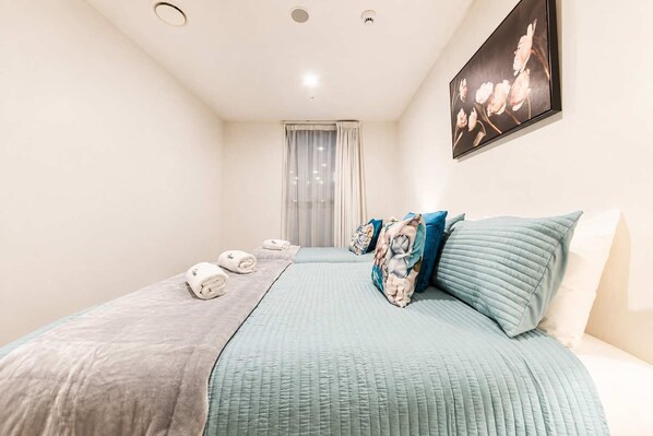 Una habitación de hotel con una cama, almohadas, una manta y toallas.
