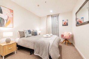 A bedroom with a bed, bedside tables, a chair, and artwork on the walls.
