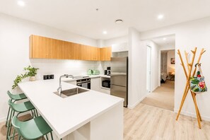 A modern kitchen with a central island, stainless steel appliances, and wooden cabinets.