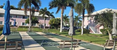Un espacio al aire libre soleado con una cancha de juego de hoquey, bancos y sombrillas.