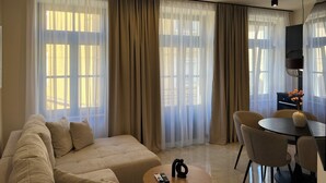A modern living room with a beige sofa, a round coffee table, and a dining area with chairs and a table. - Luxury apartman Central 1, Crikvenica (Crikvenica)