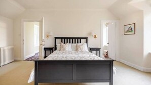 A bedroom with a dark wooden bed, white walls, and a radiator. - The Squirrel Room Energetic & Inspiring (Kinross)