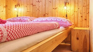 A wooden cabin-style room with two beds, each with checkered bedding and lamps on either side. - Nice apartment for 3 people with WIFI, TV and patio (Trutnov)