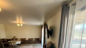 A spacious living room with a sofa set, a coffee table, and a TV mounted on the wall. - Villa panoramic view (Narbonne)