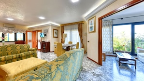 A spacious living room with a sofa, a dining table, and a TV. - Beautiful private villa for 8 guests with private pool, WIFI, A/C, TV and patio (Syracuse)
