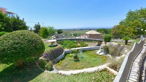 A garden with a pond, a bridge, and a building in the background. - Beautiful private villa for 8 guests with private pool, WIFI, A/C, TV and patio (Syracuse)