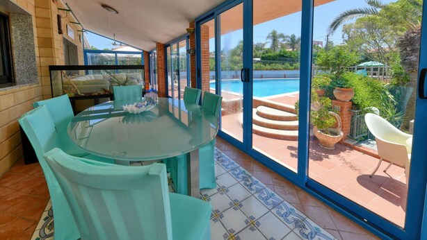 A sunlit room with a glass table and chairs, a pool visible through large sliding doors, and a tiled floor. - Beautiful private villa for 8 guests with private pool, WIFI, A/C, TV and patio (Syracuse)