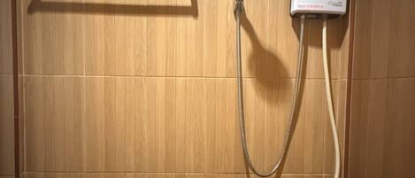 Ducha con cabezal de ducha manual y panel de control en la pared.
