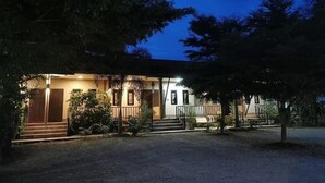 A two-story building with a porch, steps leading to the entrance, and a well-lit exterior. - Hug Wang Homestay (Wang Saphung)