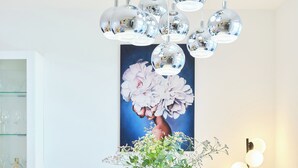 A dining area with a marble table, blue upholstered chairs, a vase with flowers, a painting of flowers, and a chandelier. - Hedera Estate, Hedera A54 (Zupa dubrovacka)