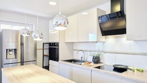 A modern kitchen with white cabinets, a wooden countertop, a built-in stove, and pendant lights. - Hedera Estate, Hedera A54 (Zupa dubrovacka)