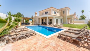 Une maison à deux étages avec une piscine, un espace extérieur aménagé et un jardin bien entretenu.
