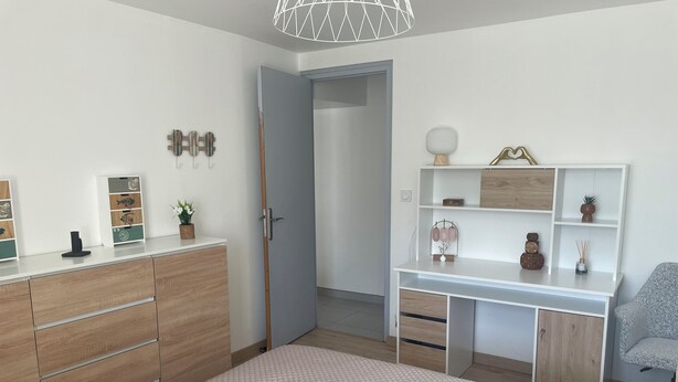 Een moderne slaapkamer met een bed, bureau en garderobe.