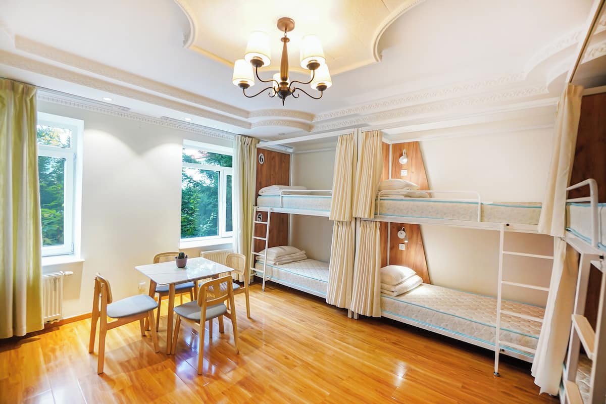 A room with bunk beds, a dining table with chairs, and a chandelier.