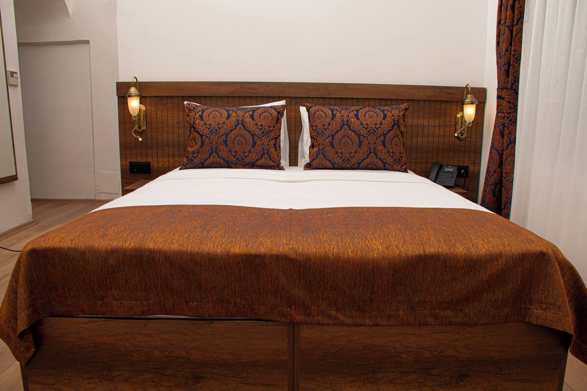 A large bed with a wooden headboard, two bedside lamps, and a telephone on the nightstand.