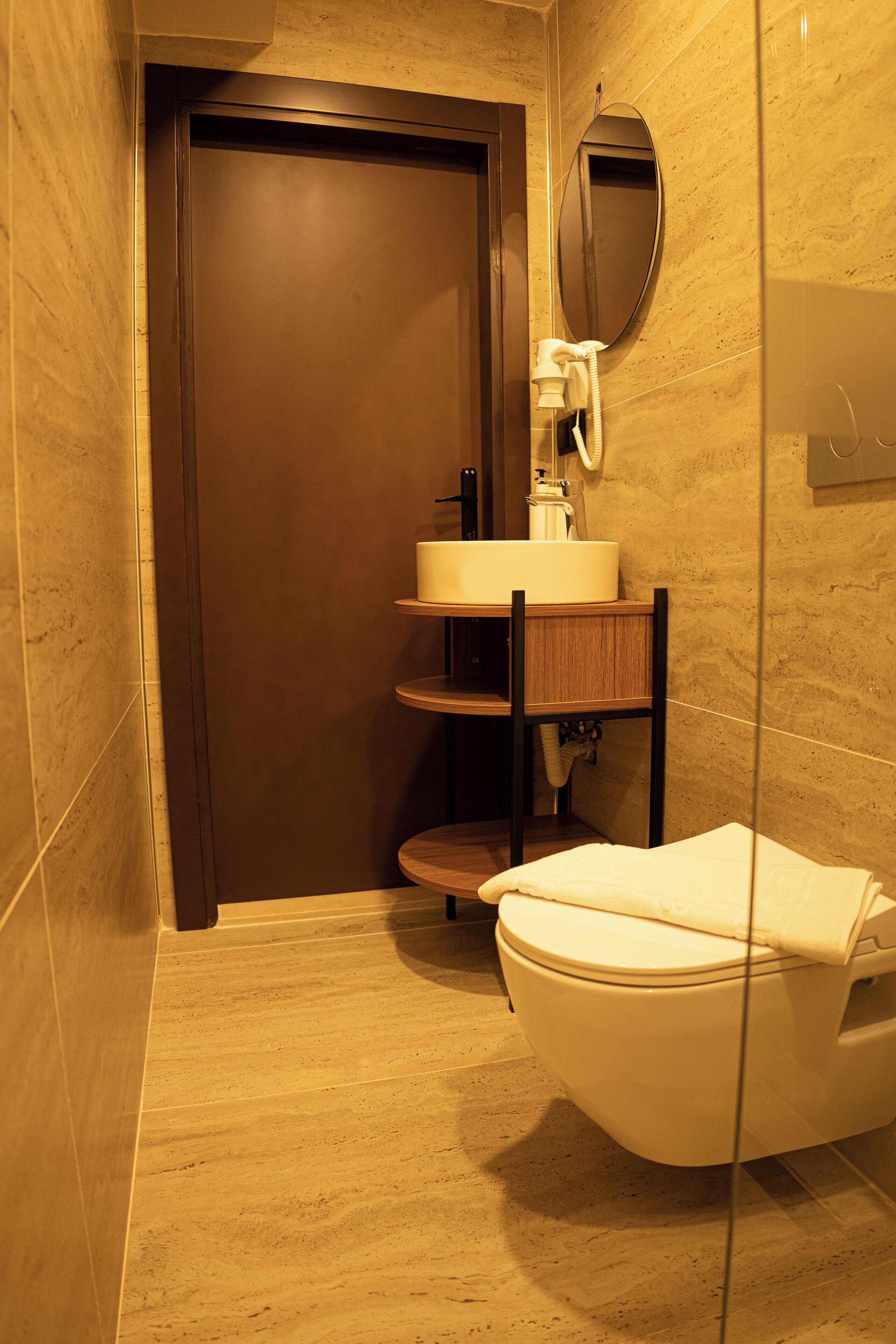 A bathroom with a toilet, a sink, a mirror, and a door.