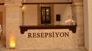 Un espace d’accueil avec une enseigne indiquant « RÉCEPTION » et « TASHAN » au-dessus d’une porte.