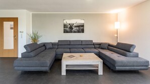 Un salon moderne avec un canapé d’angle, une table basse, un tableau accroché au mur et un lampadaire.