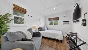 Een kamer met twee bedden, een slaapbank, een televisie en een ventilator.