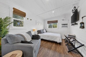 Une chambre avec deux lits, un canapé, une télévision et un ventilateur.