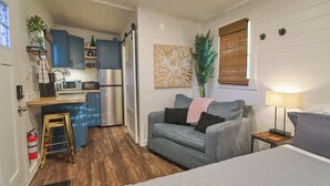 Ein kompakter Wohnbereich mit Küchenzeile, einer Couch, einem Nachttisch und einer Lampe.