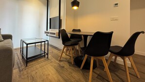 Een moderne eetruimte met een glazen tafel, zwarte stoelen en een hanglamp.