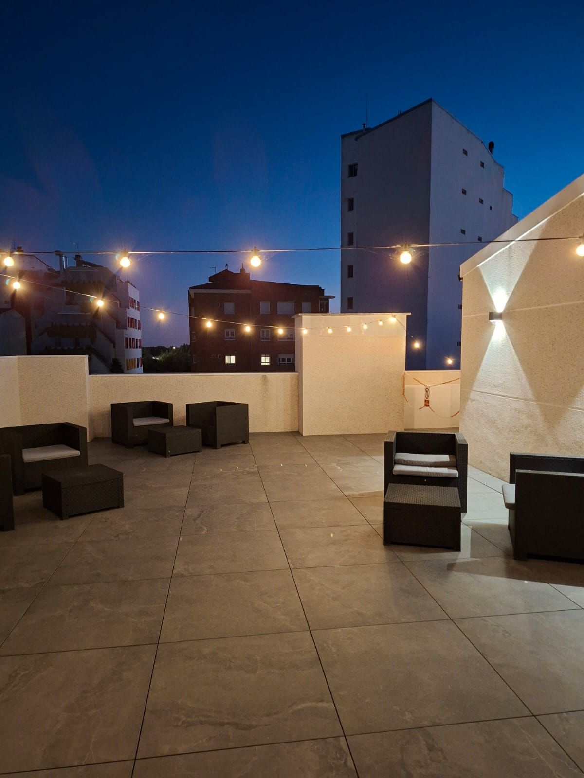 A rooftop terrace with outdoor seating and string lights.