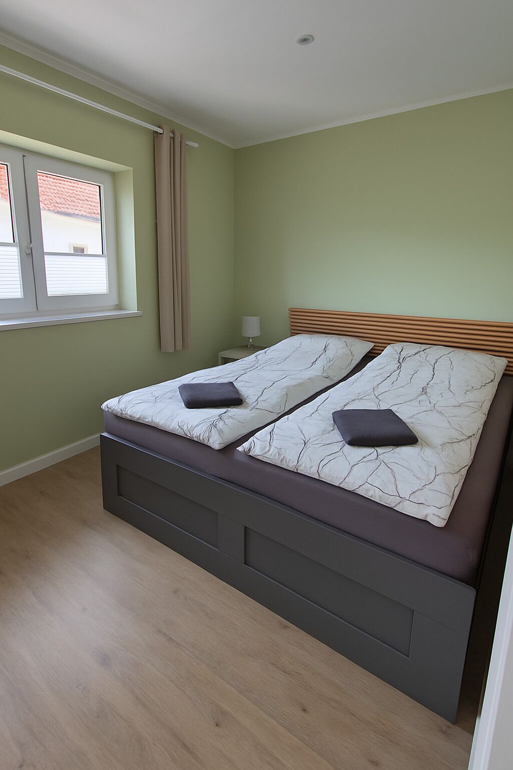 Ein Schlafzimmer mit einem Bett, einem Fenster und einem Nachttisch.