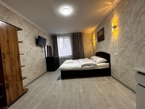 Une chambre à coucher avec un lit, un téléviseur, une armoire en bois et un mur décoré d’un motif marbré.