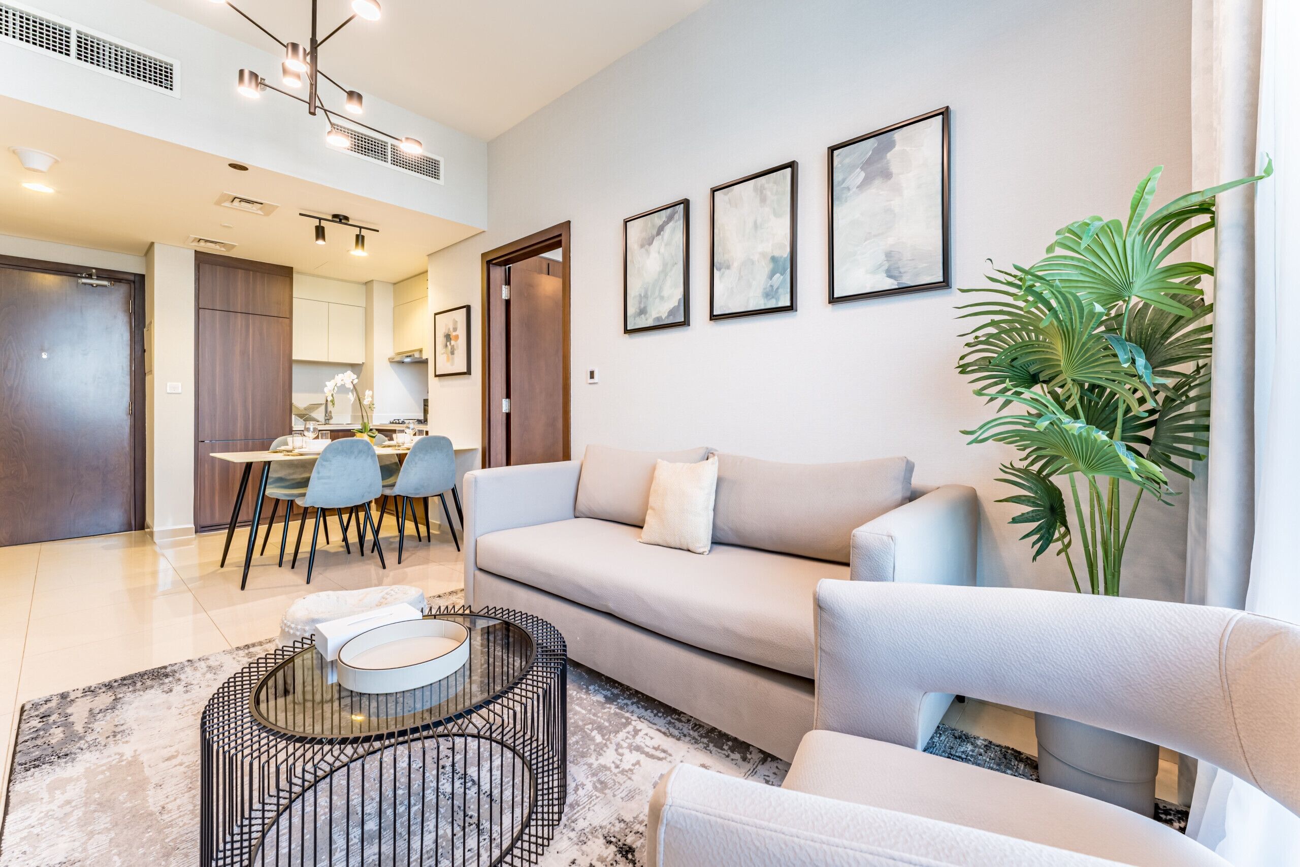A modern living room with a sofa, a coffee table, and a dining area with chairs and a table.