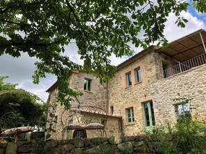 A stone building with a balcony, a wrought iron bench, and a stone wall. - Terrace over poetry (Toscana)