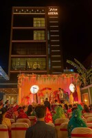 Evento en interiores con un escenario y audiencia frente a un edificio con el letrero 'ARENA'.