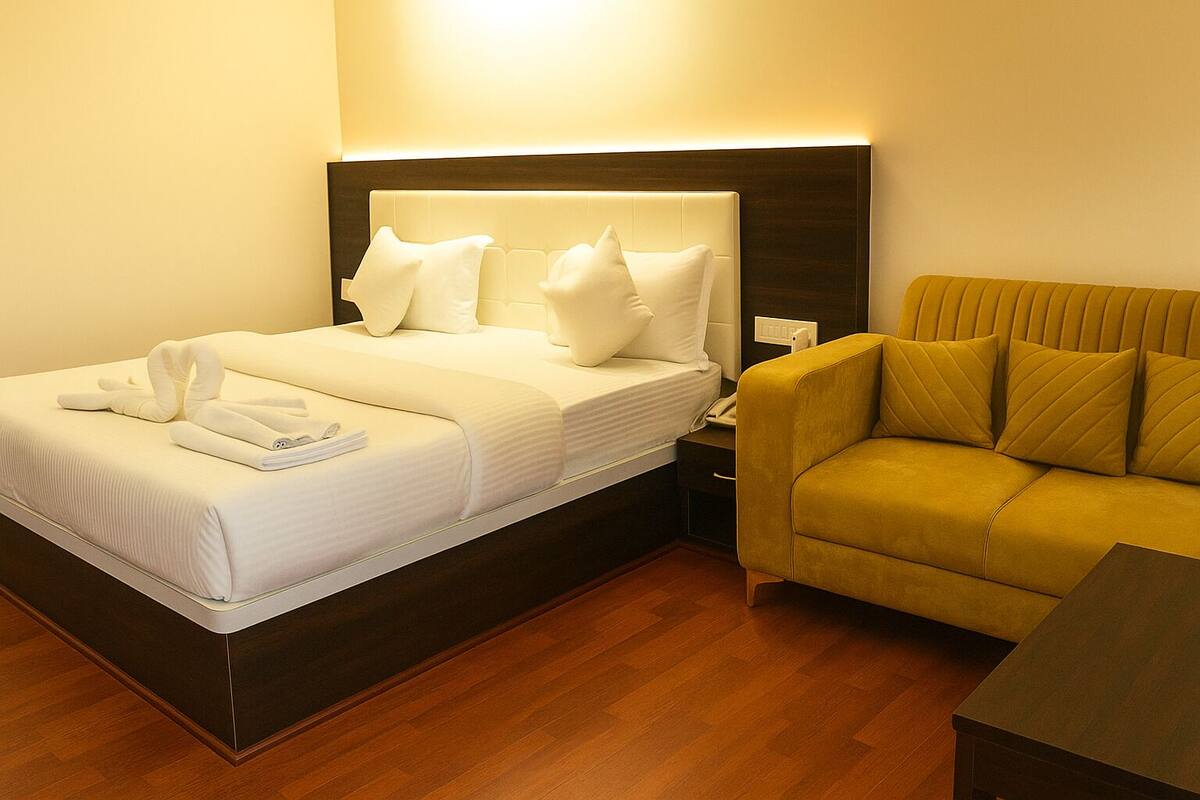 Een hotelkamer met een bed, nachtkastje, bank en een houten vloer.