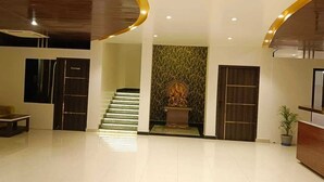 A modern lobby with a staircase, a reception desk, and a decorative wall. - HOTEL JVW ARENA (Motihari)