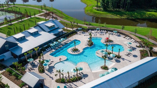 Un resort con un amplio espacio de piscina, numerosas tumbonas y un edificio con techo azul.