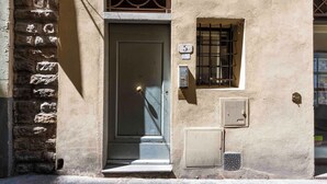 A building with a stone wall, a door, and a window with bars. - Deluxe Pitti Suites by MMega (Florence)