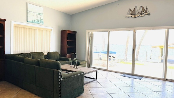 A living room with a green sofa, a coffee table, and a view of the outdoors through a sliding glass door.
