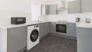 Eine moderne Küche mit Waschmaschine, Mikrowelle, Backofen und Spüle.