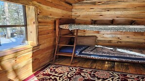 Una cabaña con una cama litera, una ventana y una alfombra estampada.