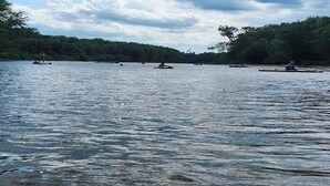 Un lago tranquilo con varias embarcaciones y una orilla bordeada de bosque.