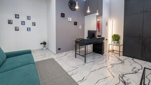 A modern living room with a teal sofa, a marble floor, a desk with a computer, and a large wardrobe. - Terrazza Moio (Naples)