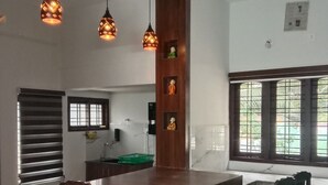 Una cocina moderna con una isla central, sillas de madera, luces colgantes y un ventanal con barandillas.
