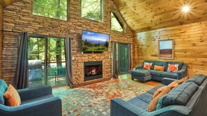 A spacious living room with a fireplace, large windows, and a cozy seating area. - Budget-Friendly! Creekside, Hot Tub, Firepit (Gatlinburg)