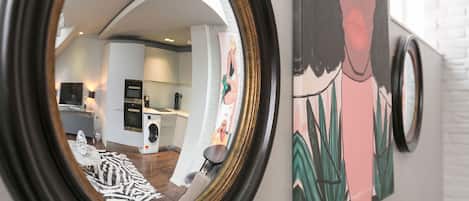 A round mirror reflecting a modern kitchen with white cabinetry, a built-in oven, and a washing machine.