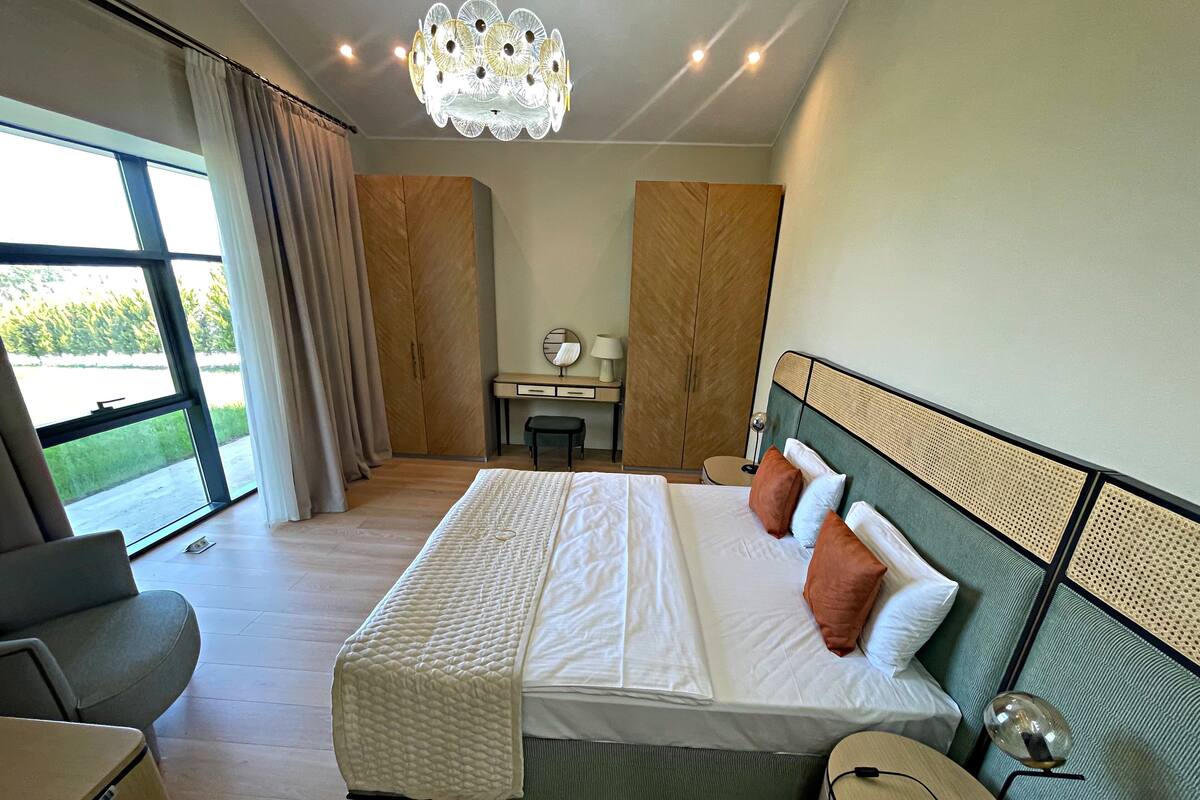 Un dormitorio moderno con una cama grande, un escritorio y vistas al exterior.