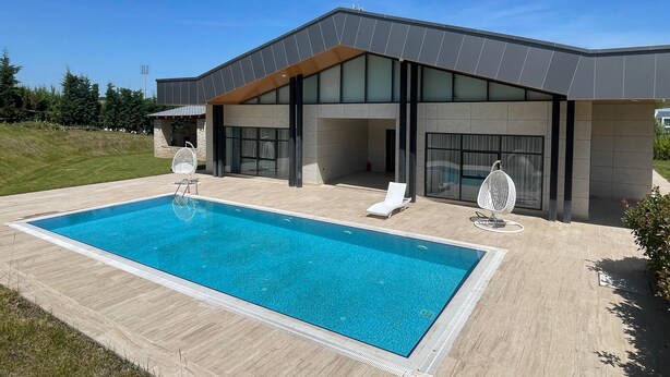 A modern house with a swimming pool, large windows, and outdoor seating.