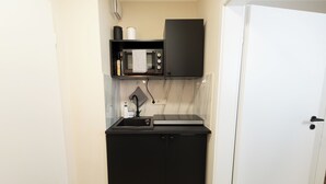 A compact kitchenette with a microwave, a small sink, and a cabinet.