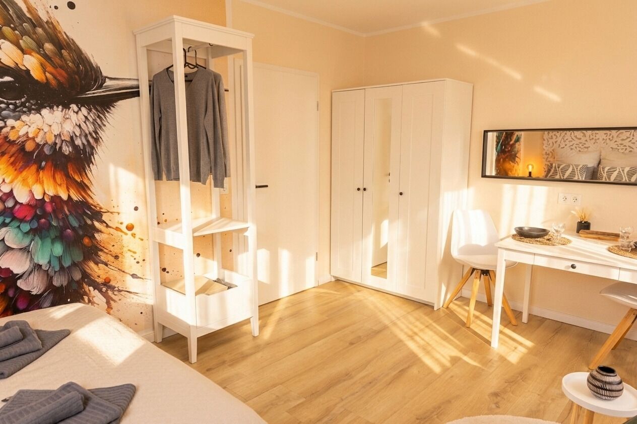 Ein Schlafzimmer mit einem Bett, einem Schrank, einem Schreibtisch und einem Stuhl.